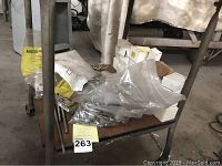 Photo of a metal cart with various hardware items in bags and boxes, including bolts and nuts.