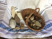 Full view of rock collection and woven basket on cloth backdrop showing various rock types and sizes