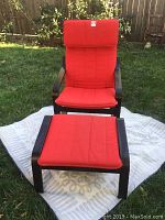 Front view of red lounge chair with ottoman on outdoor mat, wooden frame and red cushions visible.