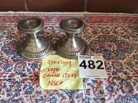 Pair of tarnished sterling silver NS Co. candlesticks with rope design on a patterned textile.
