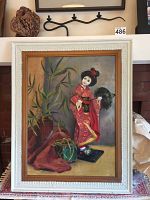 Front view of framed oil painting depicting a Japanese doll in a red kimono with bamboo plants and a green vase in the background, set in a white wooden frame.