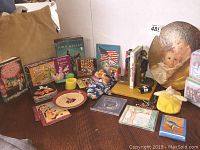 Multiple vintage children's books and CDs displayed with brass bookends and other toys on a table.