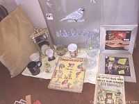 Overall view of lot showing mugs, books, framed albums, mirror, wine glasses and welcome plaque with bird