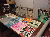 Photo of glassware with six crystal port glasses and five wine goblets, alongside a variety of sheet music and songbooks.