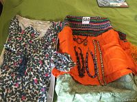 Four necklaces, three scarves, and Boden top arranged on green surface