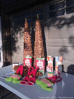 Two tall dried grape vine cone trees, pine cones, holiday decorative blocks, and holiday pouches on table