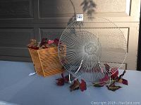 Gray coated iron platter, asymmetrical iron basket, and decorative vine displayed on a table against a garage door background in natural light.