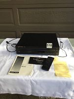 Full view of the Harman Kardon FL 8450 CD player with remote, manuals, and documents laid out on a white cloth.