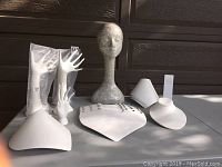 Photo showing all display pieces including the newspaper print mannequin head, ceramic hands, necklace cones, and the earring stand arranged on a table.