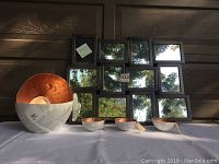 Photo showing multi-panel copper framed wall mirror and set of five copper paper lined paper-mache bowls, two large and three small, on display surface with outdoor background.