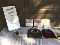 Photo showing the Hipster Combo cardboard wall art packaging standing upright with instructions, two Loop Works neoprene tablet cases in red and gray colors, and seven packaged Mighty Case Tyvek tablet cases with assorted prints including flags and vintage themes.