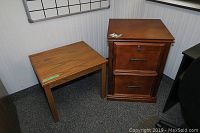 Wood file cabinet and parsons style side table together in corner of room with carpet flooring and a whiteboard on the wall