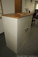 Sandusky metal cabinet with locking double doors and woodgrain top viewed from angle