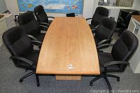 Top view of the rectangular wooden conference table with six black office chairs arranged around it