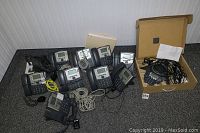 Ten Cisco SPA 300 series IP phones along with Polycom SoundStation IP 6000 conference phone and cables on floor.