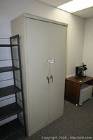 Front view of ABUS metal storage cabinet with closed double doors and two handle locks, showing a light gray finish and rectangular shape.