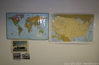 Two large maps hung on wall. Left is a world map poster with colorful countries. Right is a detailed US map poster with geographic features and roads.