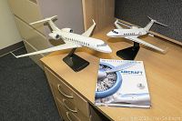 Two white model airplanes on black stands and a hardcover aircraft history book on wooden desk.