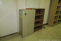 Photo of beige metal file cabinet with stickers and beige metal book shelf beside it, corner view