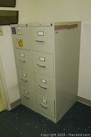 Photo of two light gray HON filing cabinets side by side against a wall, showing front drawers and handles.
