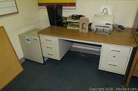 Full view showing the metal desk with wood finish top, drawers on both sides, and the Sharp metal cabinet next to it with some office equipment on desk.