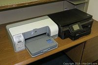 HP Photosmart D5160 and Photosmart 6515 printers side by side on wood desk.