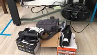 Photo showing two Sony HDR-CX220 camcorders on retail boxes, Logic case, and radio/CD player all placed on the floor.