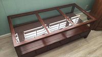 Top view showing the three glass panels on the wooden coffee table and the interior storage space.