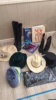 Photo of boots, hats, and books together on floor: two pairs of boots, multiple hats, and three books