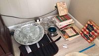Cookbooks stacked in corner with serving platters, glass containers, and knife set displayed on countertop
