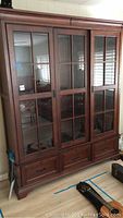 Front view of the Aspen Home china cabinet showing three glass doors with wooden grid muntins and three lower drawers.