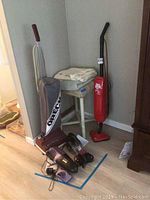Photo showing Oreck upright vacuum, Dirt Devil stick vacuum, Shark cordless vacuum with charger, Pet Hair Eraser attachment, stool, and two towels