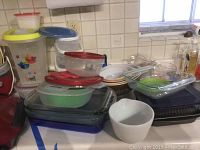 Various glass baking pans and bowls stacked with plastic storage containers