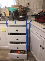 Kitchen drawers taped shut containing various kitchen utensils and flatware.