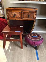 Front view of a wood end table with two small drawers, rectangular wooden stool, and round upholstered stool with fabric seat.