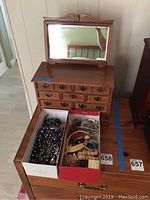 Wooden jewelry boxes with costume jewelry in two shoeboxes on top of one of the boxes.