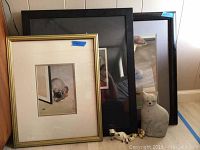 Two framed cat prints, hollow cat door stop, four small cat figurines on the floor