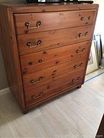 Full view of the chest of drawers showing five drawers with brass handles.