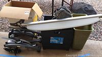 Photo showing various items including Saris bike rack, trunk cover, black plastic tote, green trash can, and cardboard box.