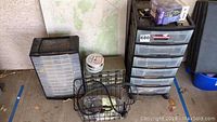 Two Connect-A-Drawer multi-drawer cabinets next to wire basket, spool of wire, and picture frame leaning against wall.