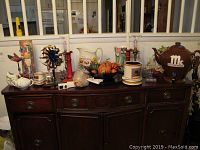 Wide view of all items arranged on a dark wooden sideboard, showing the electric lumieres, wine box, drink dispenser, pitcher, and decorative items.