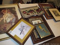 Overview of multiple framed art pieces, table runner with fruit motif, and mirror on floor