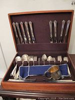 Open wooden box showing top row of dinner knives in Damask Rose pattern