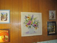 Various wall art pieces including floral painting, Lyceum Little Cigars vintage ad poster, and other framed pictures arranged on wood panel walls.