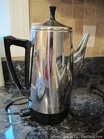 Electric stainless steel kettle with black handle and base on kitchen counter
