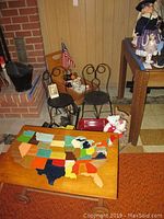 Pair of metal doll chairs, wooden chair with American flag, small red Radio Flyer wagon, plush toys, and a wood puzzle map table showing various US states.