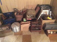 Wide image showing assortment of items including bird cages, metal lock box, baskets, and boxes on floor