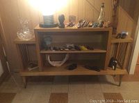 Wide shot of wooden console displaying miniature shoes on shelves, glass bowl, pitcher, wood statue, lamp, and cast iron doorstop