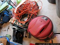 Wide photo showing Toro electric Super Blower Vac, Shop Vac, and extension cords piled on floor in garage or workshop area.