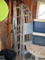Overview of three ladders stacked together in storage, showing signs of heavy use and paint marks.
